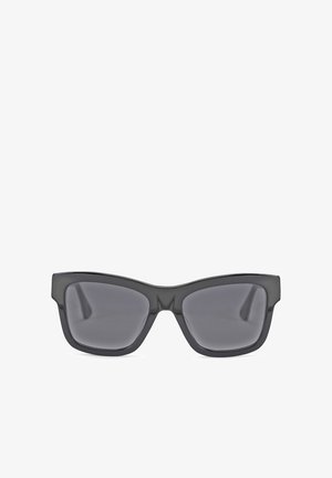 Schwarze Sonnenbrille mit dickem, eckigem Rahmen, ausgestattet mit dunklen Gläsern und einer glatten, glänzenden Oberfläche. Die Form erinnert an ein modifiziertes Cat-Eye-Design.