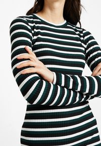 Langärmliges Kleid mit gerippter Textur, schwarzen, weißen und türkisfarbenen horizontalen Streifen, Rundhalsausschnitt und figurbetontem Schnitt.