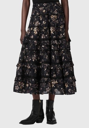 Jupe midi noire à volants avec motif floral, associée à des bottines en cuir noir avec fermetures éclair latérales et talons blocs.