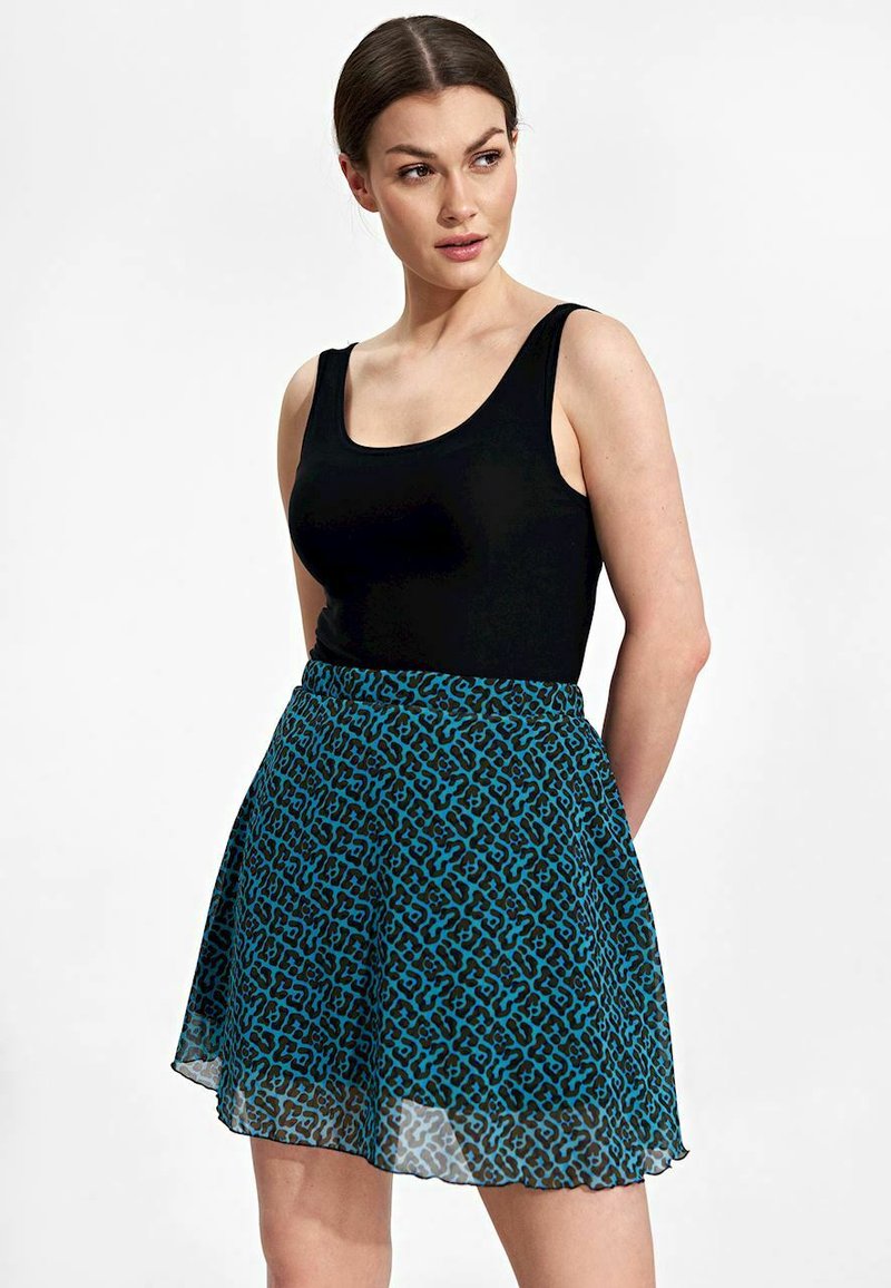 Zwarte mouwloze top gecombineerd met een teal gekleurde rok met een patroon, voorzien van een doorschijnende overlay en een uitlopende ontwerp. Geen extra accessoires of details zichtbaar.