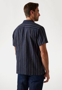 Camisa de manga corta, de color azul oscuro, con rayas verticales en blanco y verde, que presenta un cuello clásico y un corte recto.