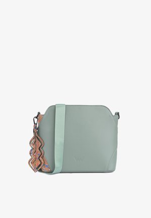 Zelená syntetická kožená crossbody taška s texturovaným korkovým akcentem, zdobená vzorovaným přívěskem a nastavitelným popruhem. Obdélníkový design.