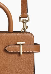 Borsa a mano in pelle marrone con un design strutturato, dotata di dettagli in metallo color oro e cuciture bianche lungo i bordi.