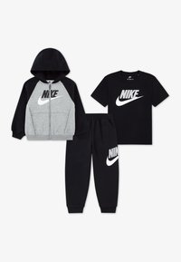 Ensemble de vêtements Nike en trois pièces : un hoodie gris zippé, un t-shirt à manches courtes noir et un pantalon de survêtement noir. Chacun arbore le logo Nike de manière proéminente.