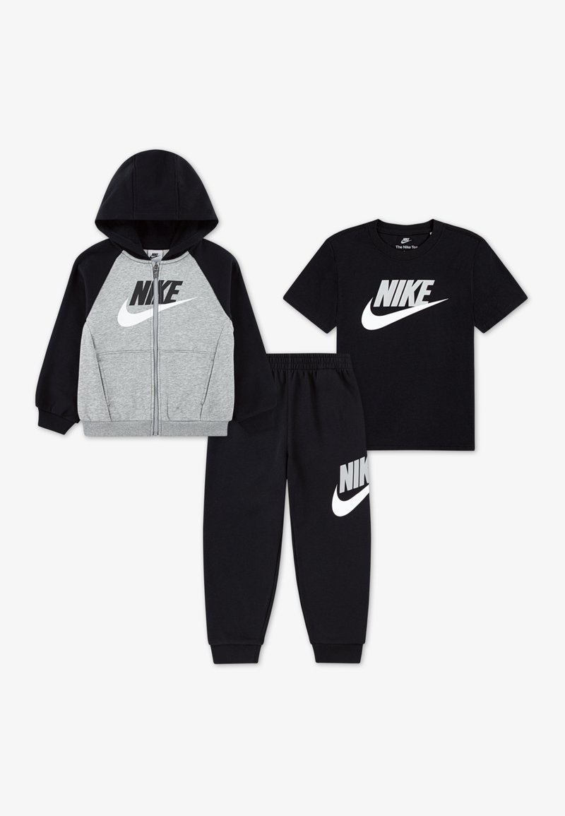 Ensemble de vêtements Nike en trois pièces : un hoodie gris zippé, un t-shirt à manches courtes noir et un pantalon de survêtement noir. Chacun arbore le logo Nike de manière proéminente.