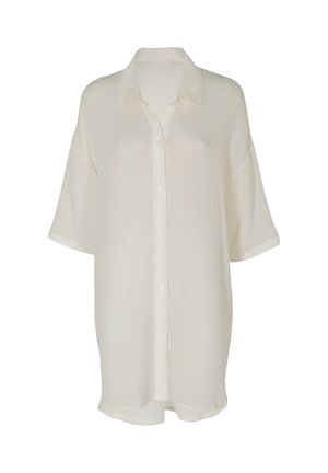 Camicia a maniche corte, larga, color avorio chiaro con bottoni, colletto ampio e tessuto strutturato, mostrata su uno sfondo semplice.