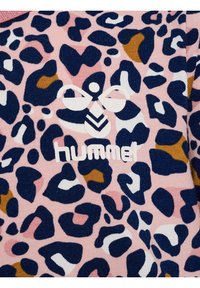 Tela rosa con un patrón de leopardo en navy, blanco y mostaza, que presenta un logo de Hummel en blanco con una abeja estilizada y texto.