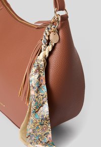 Hn�ědá kožená kabelka s texturou a zlatým kováním, zdobená pletenou stuhou a květinovým šátkem.