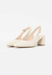 Vaaleanbeige slingback-korkokengät, joissa on teräväkärkinen muotoilu, valmistettu sileästä materiaalista. Kengissä on säädettävä vyö, jossa on kultainen solki, ja matala lohkokorko.