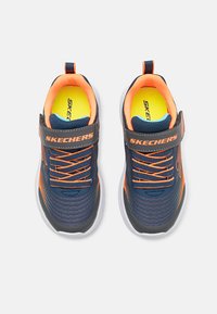Baskets marines et grises avec des accents orange, tissu texturé, lacets élastiques et une sangle Velcro. Semelle intérieure rembourrée avec une doublure jaune vif.