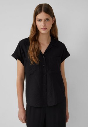 Camicia nera a maniche corte con bottoni, dotata di colletto, due tasche frontali e una finitura in tessuto testurizzato.
