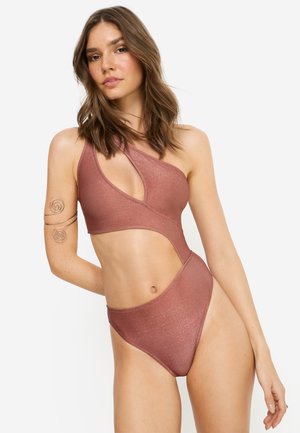 Einteiliger Badeanzug in Roségold, mit Cut-out-Design und asymmetrischem Träger. Hergestellt aus glänzendem, glattem Stoff mit hoch ausgeschnittenen Beinausschnitten.
