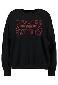 Czarny sweter z luźnym krojem, z czerwonym napisem "DZIĘKUJĘ ZA NIC" oraz ściągaczami przy mankietach i u dołu. Miękka tekstura materiału.