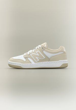 Beige and white low-top sneaker with perforated toe, white laces, and a large "N" logo on the side, shown from the outer side.