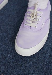 Baskets en toile lilas clair avec des lacets et une semelle blanche, présentant une texture lisse et un petit logo sur le côté.