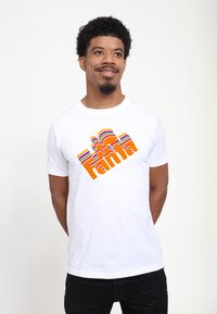 Witte katoenen t-shirt met een kleurrijk retro-stijl "Fanta" logo met golvende, meerkleurige strepen in oranje, roze, paars en groen.