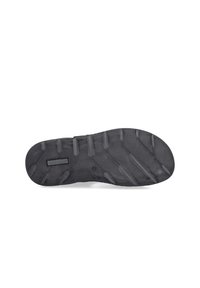 Semelle de chaussure en caoutchouc noir avec surface texturée, présentant des crampons de traction proéminents et un logo rectangulaire au centre.