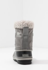Bota cinza à prova d'água com um colarinho felpudo de cor creme, sola de borracha e marca Sorel. Tecida texturizada com pormenores em pele.