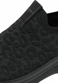 Black slip-on shoe with textured knit material featuring a subtle leopard pattern. Rubber sole with a low-profile design. Accented with a top pull tab.