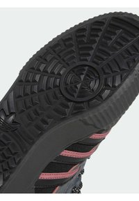 Suela de zapato de goma negra con un patrón de banda de pescado; presenta rayas rosas y un borde texturizado; logotipo circular en el centro.