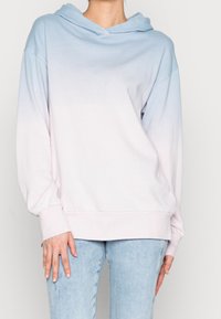 Sudadera ligera con un diseño de ombre que presenta un degradado desde el azul claro hasta el rosa suave. Hecha de una tela suave con un corte relajado y mangas largas.
