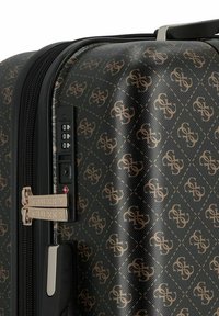 Zwarte harde koffer met een geometrisch monogram patroon in goud. Inclusief een TSA-combinatieslot en dubbele ritsen met gebrandmerkte hardware.