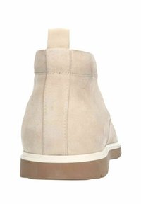 Bottines en daim beige avec une texture lisse, un design élancé, un bout arrondi doux et une semelle en caoutchouc blanche. Présentent une languette en boucle à l'arrière.