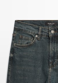Mörkblå jeans i denim med framficka, bältesöglor, metallknapp och synlig "Massimo Dutti"-etikett på midjebandet.