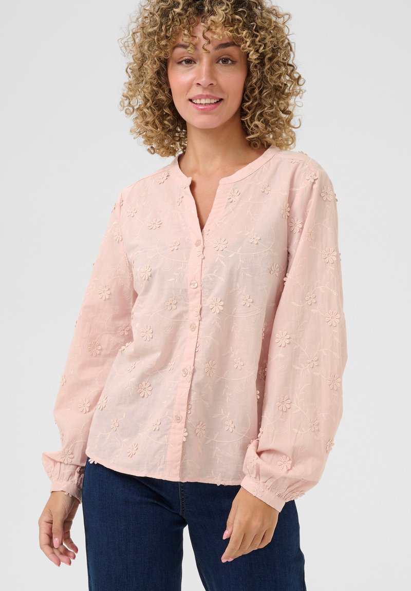 Light pink button-up blouse with long puffed sleeves, featuring floral embroidery and a round neckline. Soft, textured fabric with detailing.
