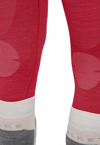 Rote Leggings mit strukturiertem Design, leichten roten kreisförmigen Mustern und einem mehrfarbigen gerippten Bund in Grau und Weiß.