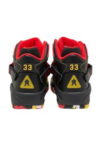 Zapatos de cuero negro de caña alta con acolchado rojo, acentos amarillos y una suela de varios colores. Presentan un logotipo en forma de triángulo amarillo en los talones.