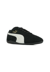 Sneaker in suede nero e grigio con una finitura testurizzata, dotata di un logo Puma dorato, lacci neri e una suola in gomma. Design classico a bassa altezza.
