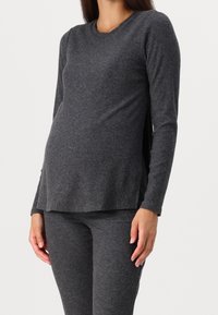 Grå ribbat långärmad topp med rund halsringning och sidofickor, i kombination med matchande tighta byxor. Mjukt stickat material med en texturerad yta.