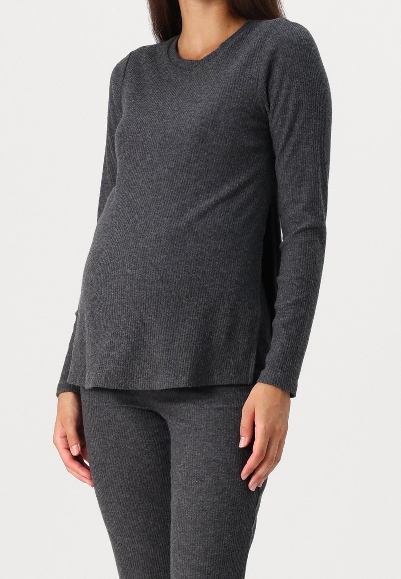 Grå ribbat långärmad topp med rund halsringning och sidofickor, i kombination med matchande tighta byxor. Mjukt stickat material med en texturerad yta.