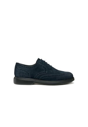 Scarpe da uomo in suede blu navy, modello brogue, con suola nera, chiusura con lacci e perforazioni decorative sul lato e sulla punta.
