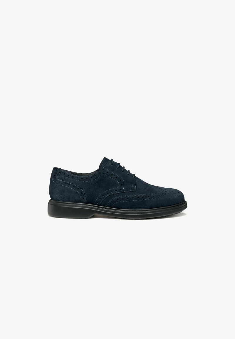 Scarpe da uomo in suede blu navy, modello brogue, con suola nera, chiusura con lacci e perforazioni decorative sul lato e sulla punta.