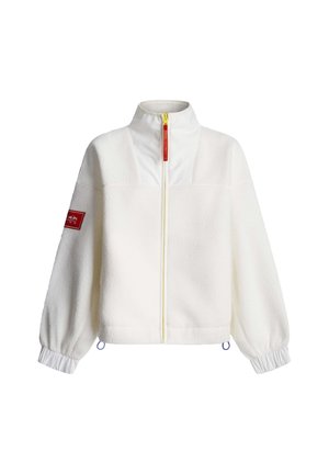 Λευκό φλις μπουφάν με ψηλό γιακά, κίτρινο φερμουάρ και ελαστικές μανσέτες. Διαθέτει κόκκινο έμπλαστρο στο αριστερό μανίκι και μπλε κορδόνια για ρυθμιζόμενο σφιξίμο.