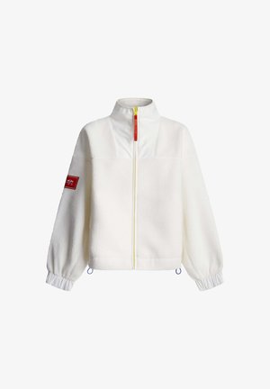 Biela fleecová bunda s vysokým golierom, žltým zipsom a elastickými manžetami. Na ľavom rukáve má červenú nášivku a modré šnúrky na stiahnutie.