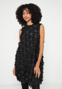 Μαύρο φόρεμα με στρωμένα υφασμάτινα λουλούδια και μοβ διακοσμητικά. Αμάνικο σχέδιο, στρογγυλή λαιμόκοψη και χαλαρή εφαρμογή. Υφή με ανάγλυφο επιφάνεια.