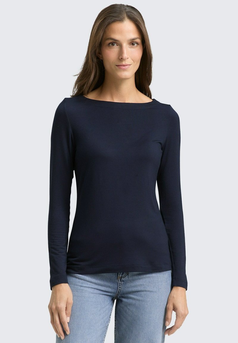 Marineblauw langemouwen top met een bootnek, gemaakt van zachte stof. Kenmerkt zich door een fitted ontwerp, gladde textuur en minimale naden.