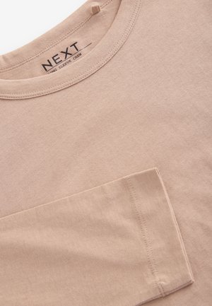 T-shirt a maniche lunghe beige in cotone morbido. Presenta un colletto rotondo e una tasca sul lato sinistro del petto. Design semplice e pulito.
