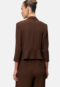 Brązowa, dopasowana marynarka z rękawami do łokcia i efektem peplum, wykonana z gładkiego materiału. Zawiera kołnierz z klapami oraz minimalne szwy.