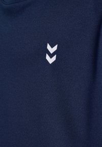 Marineblauer Stoff mit zwei kleinen weißen nach unten zeigenden Chevron-Formen, die vertikal nahe der Mitte ausgerichtet sind.