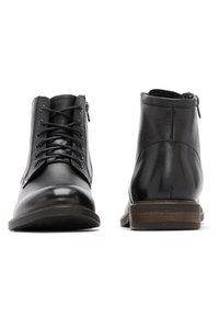 Botas de cuero negras hasta el tobillo con cordones y cremalleras laterales. Puntera brillante, parte trasera texturizada y acentos de suela de madera. Acabado suave en general.