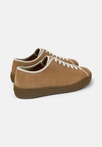 Brown suede sneakers with white laces and a textured sole, angled to show the back and side view against a plain white background.