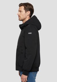 Schwarze Kapuzenjacke mit Frontreißverschluss, Seitentaschen, elastischen Bündchen und Schott-Logo am Ärmel. Verfügt über ein gepolstertes Design und eine glatte Textur.