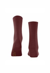 Ein Paar dunkelrote, knöchellange Socken, von hinten und von der Sohle gezeigt, mit gelbem Text auf der Sohle auf weißem Hintergrund.