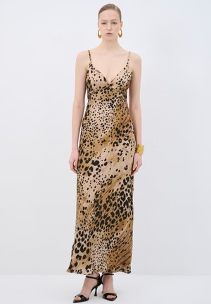 Braunes Tierdruck-Maxikleid mit dünnen Trägern, V-Ausschnitt und glatter Textur. Kombiniert mit schwarzen Absatzsandalen und einem goldenen Armband.