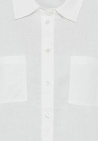 Weißes Leinenhemd mit Kragen, ausgestattet mit zwei Brusttaschen mit Klappen und einer durchgehenden Knopfleiste mit transparenten Knöpfen.
