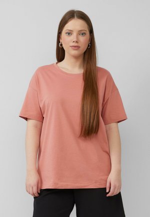 Pink cotton t-shirt with short sleeves and a round neckline, featuring a relaxed fit and smooth texture. Worn with black pants.